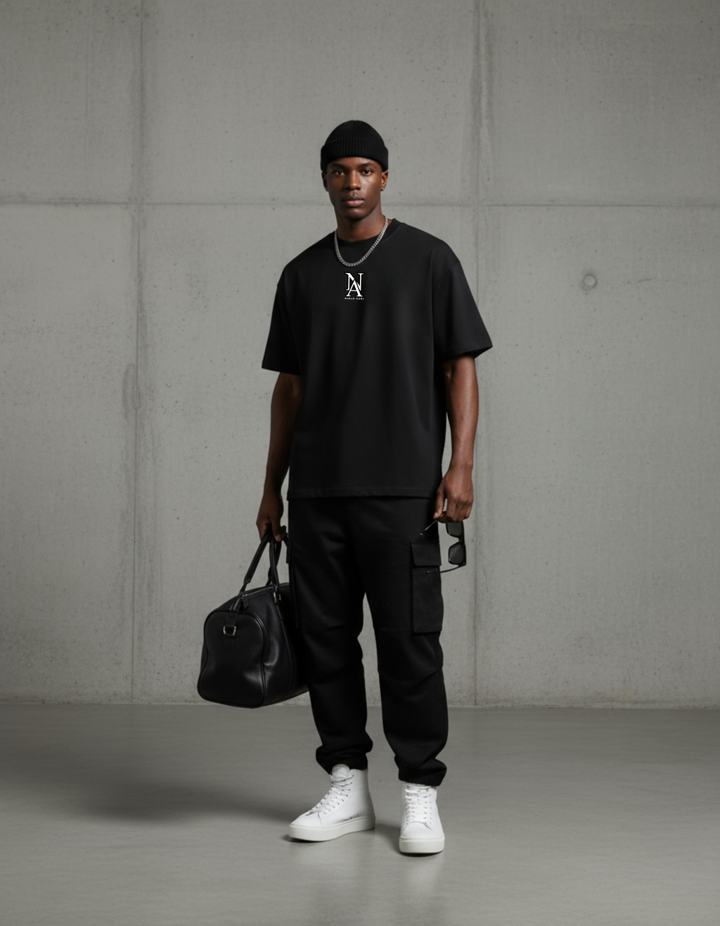 Model trägt das Niklo Auri Emblem Tee – schwarzes Oversized Shirt.“