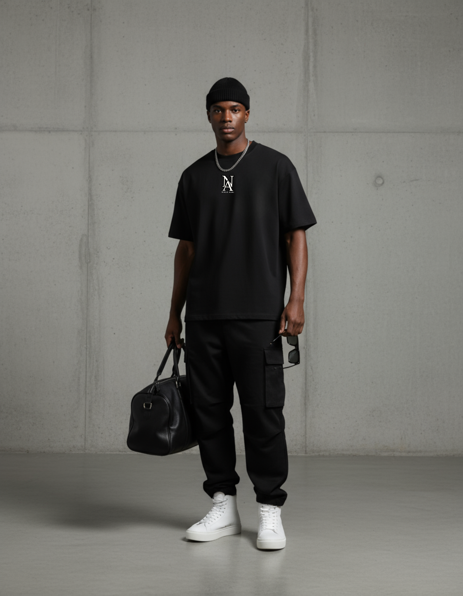 Model trägt das Niklo Auri Emblem Tee – schwarzes Oversized Shirt.“