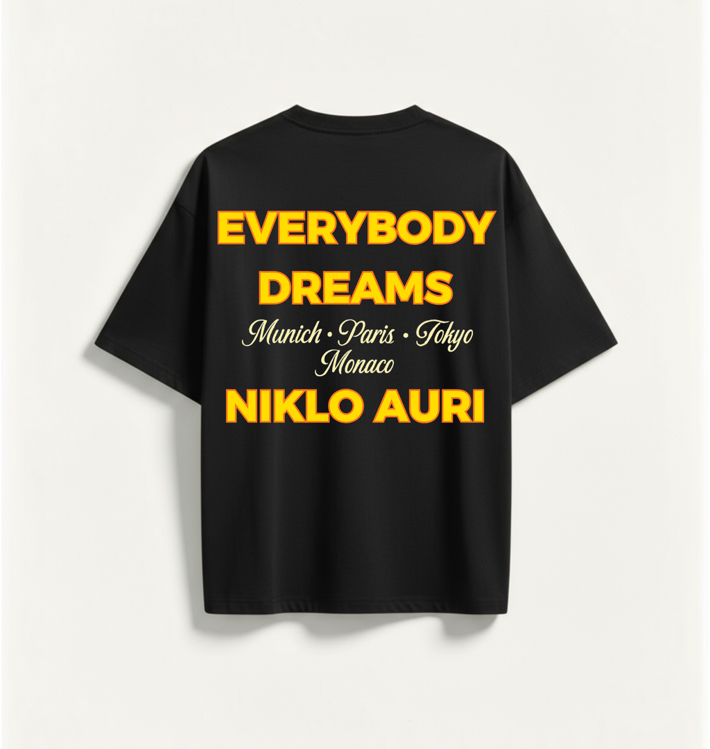 „Niklo Auri Everybody Dreams Tee – Schwarz mit gelbem Typografie-Backprint.“